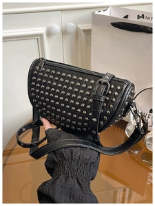 Close-up of black shell bag featuring metallic silver studs and zipper closure