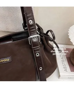Detail of adjustable shoulder strap with metal eyelets on a brown leather handbag