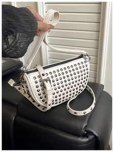 Detailed macro of white leather bag featuring polished silver metal dome rivets and zipper