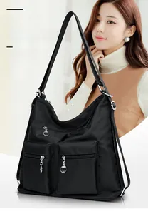 Detail of black nylon tote bag featuring two front zipper pockets and wide fabric strap