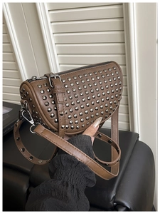Detail of dark brown crescent bag with silver rivet studs and adjustable leather strap