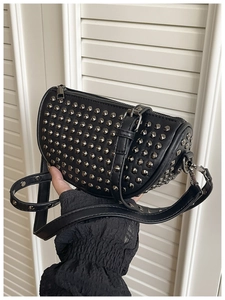 Detail of black faux leather shell bag featuring silver punk rivets and adjustable strap