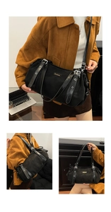 Detail of black Boston bag showing silver eyelets, adjustable strap and logo plaque