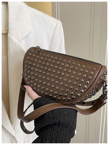 Detail shot of a dark brown crossbody shell bag featuring silver metal rivet decorations
