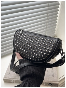 Detail shot of black leather crescent bag featuring dense silver stud embellishments