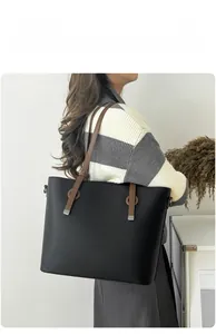 Détail du sac cabas en cuir grainé noir avec anses marron porté en bandoulière