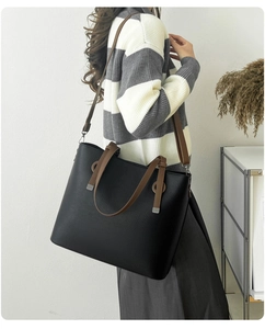 Détail d'un grand sac cabas noir avec anses marron montrant la texture et la bandoulière