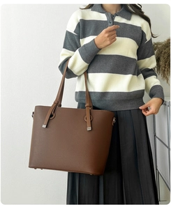Détails d'un sac cabas marron en cuir à grain litchi avec ornements métalliques et sangle