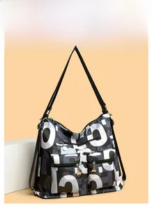 Detail view of large nylon tote bag featuring abstract letters and front zipper pockets