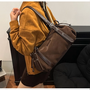 Detail of a large dark brown nylon tote bag with leather straps and metal rivets