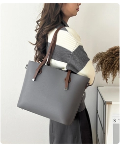 Détail du sac cabas en cuir grainé gris avec anses marron porté à l'épaule