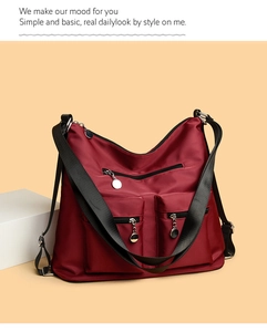 Detail showing the burgundy nylon bag texture with multiple metal ring zipper pockets