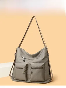 Detailed view of taupe nylon backpack with front zipper pockets and metal disk pendants