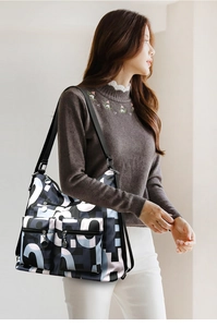 Detail of nylon bag with geometric patterns, multiple zip pockets, and adjustable strap