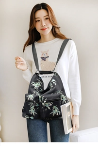 Detail of waterproof black nylon backpack featuring fresh green bamboo leaf prints