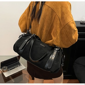 Detail of a black large capacity tote bag worn by a model in a professional office setting