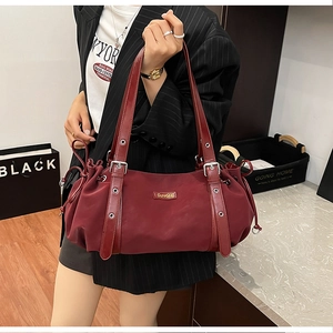 Detail of burgundy shoulder bag featuring metallic eyelets and drawstring sides
