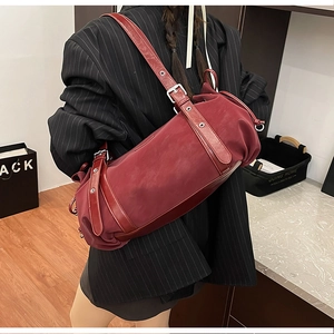 Close-up of a dark red cylindrical shoulder bag with pleated texture and silver buckle