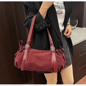 Close-up of burgundy nylon shoulder bag with adjustable eyelet straps and metal logo detail