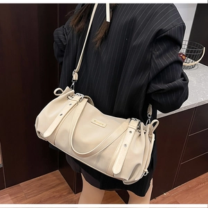 Detail of beige leather Boston bag with decorative straps and metal Suvora logo plate