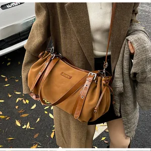 Close-up of brown suede shoulder bag with drawstring detail and silver metal logo
