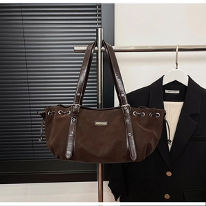 Detail view of deep brown tote bag with silver eyelets and drawstring accents