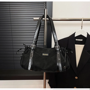 Detail of black vintage tote bag featuring a metal logo plate and side drawstring accents