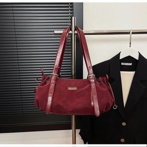 Detail of burgundy tote bag showing drawstrings and Suvora metal logo plaque