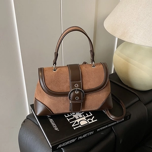 Retro patchwork brown shoulder bag with suede detail on a sofa with warm lighting