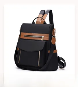 Seitenansicht des schwarzen Nylon-Rucksacks mit braunem Lederbesatz und Goldreißverschlüssen