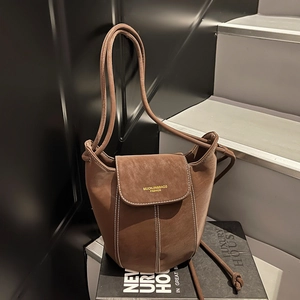 Minimalist dark brown suede bucket bag with contrast stitching and long strap