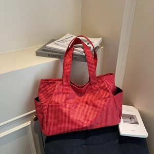 Large red plaid tote bag with side pockets on a minimal cozy lifestyle background