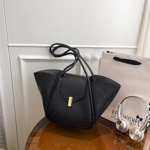 Fashionable black woven leather tote bag with gold hardware shown in a lifestyle setting