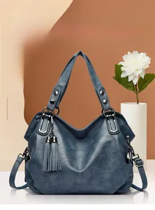 Detail of blue faux leather tote bag with silver studs and elegant long tassel fringe