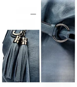 Detailed view of deep blue leather bag featuring fringe tassel and glossy metal rings