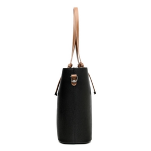 Vue latérale d'un sac cabas en cuir noir avec des poignées brunes et anneaux argentés