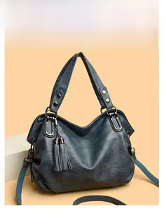 Close-up of fog blue faux leather handbag featuring litchi grain and dual tassel charms