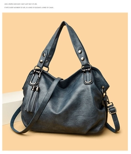 Detail of navy blue leather tote bag showing grainy texture and tassel ornament