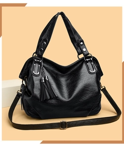 Close-up of black oil wax leather handbag featuring dual tassels and silver hardware accents