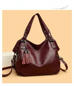 Detail of burgundy tote bag with litchi texture and decorative tassel accessory