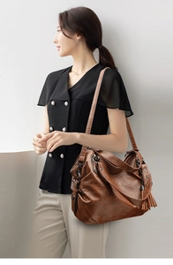 Detail of vintage brown leather handbag with long fringe tassel and rustic metal hardware