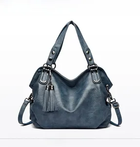 Detail of vintage blue textured handbag featuring decorative tassels and gunmetal hardware