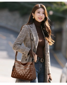 Detail of dark brown leather crossbody bag with quilted stitching and multi-zipper design