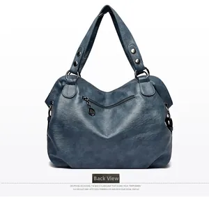 Back view of deep blue leather handbag featuring a zipper pocket and metallic ring detail