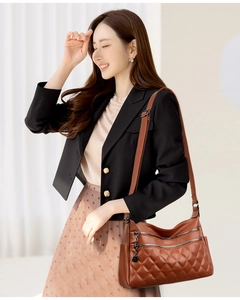 Detail of brown quilted faux leather shoulder bag with zipper pockets and adjustable strap