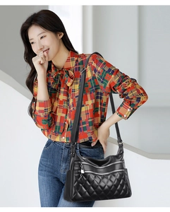 Detail of black quilted leather shoulder bag with multiple zippers and wide strap