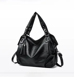 Close-up of black faux oil wax leather tote bag featuring elegant side tassel details