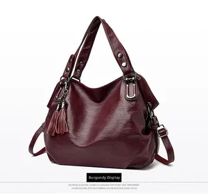 Detailed view of burgundy pebbled leather tote bag with tassels and rivet handle details