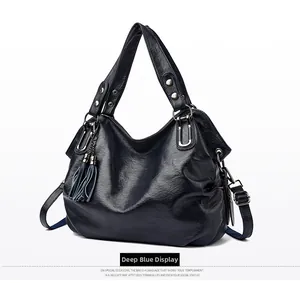 Detail of dark blue faux leather tote bag with silver hardware and tassel charm
