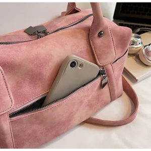 Detail of dusty pink faux suede tote bag showing front zipper pocket with a smartphone